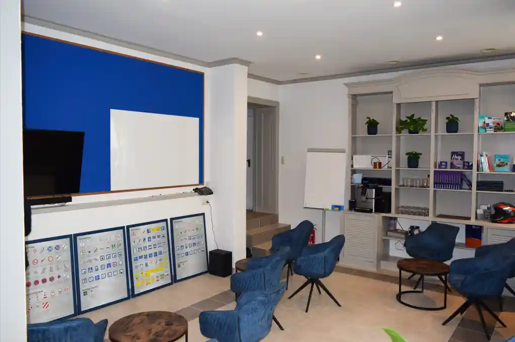 Home 15 Schulungsraum in der Fahrschule "Fahrkompetenz" in Görlitz. Es stehen gemütliche Sessel bereit für den Unterricht in angenehmer Atmosphäre. Im Regal erkennt man Schulungsmaterial.