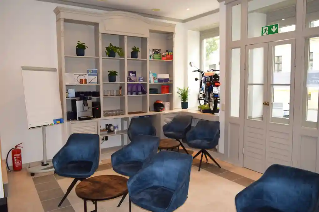 Home 16 Schulungsraum in der Fahrschule "Fahrkompetenz" in Görlitz. Es stehen gemütliche Sessel bereit für den Unterricht in angenehmer Atmosphäre. Ein blaues Simson Moped steht im Schaufenster.